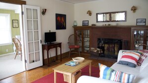 A living room with a fireplace, a television, a bookshelf, and a door leading to another room.