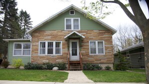 A two-story house with a stone facade, a front porch, and a small front yard.