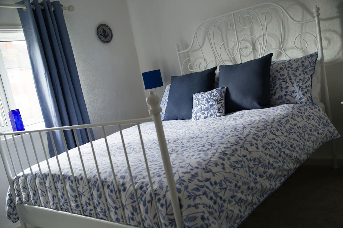 A bed with a white metal frame and a floral-patterned bedspread.