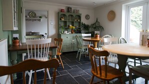 Un coin repas avec une table ronde et des chaises, un meuble vert avec des étagères et une plante en pot.