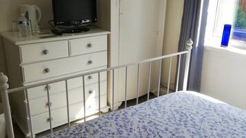 Una camera da letto con un letto, una cassettiera, una televisione e una finestra con tende.