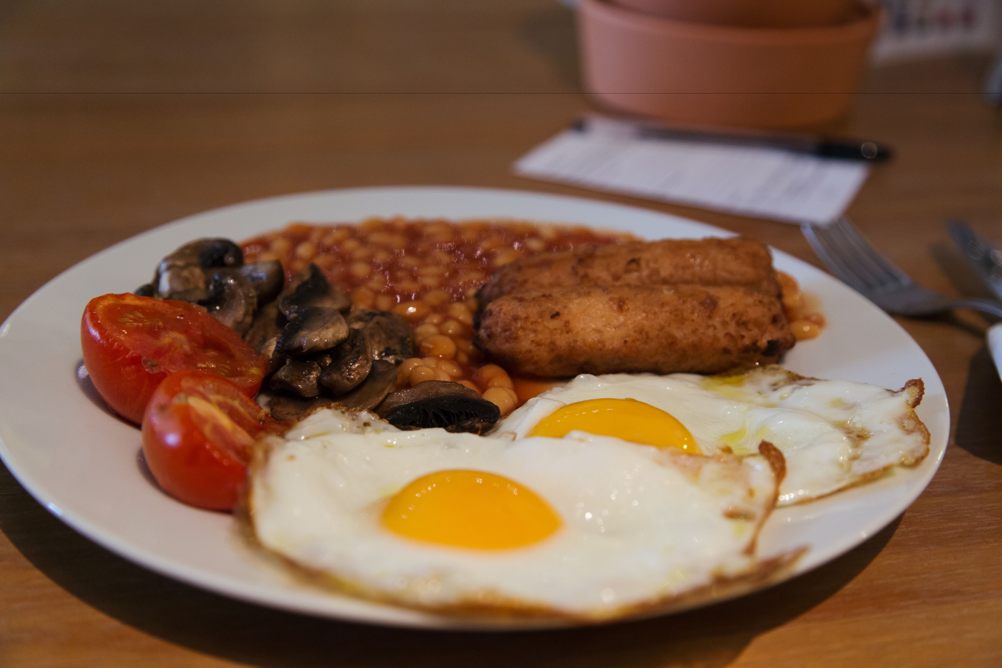 Un plato de comida con huevos, champiñones, tomates, frijoles y salchichas.