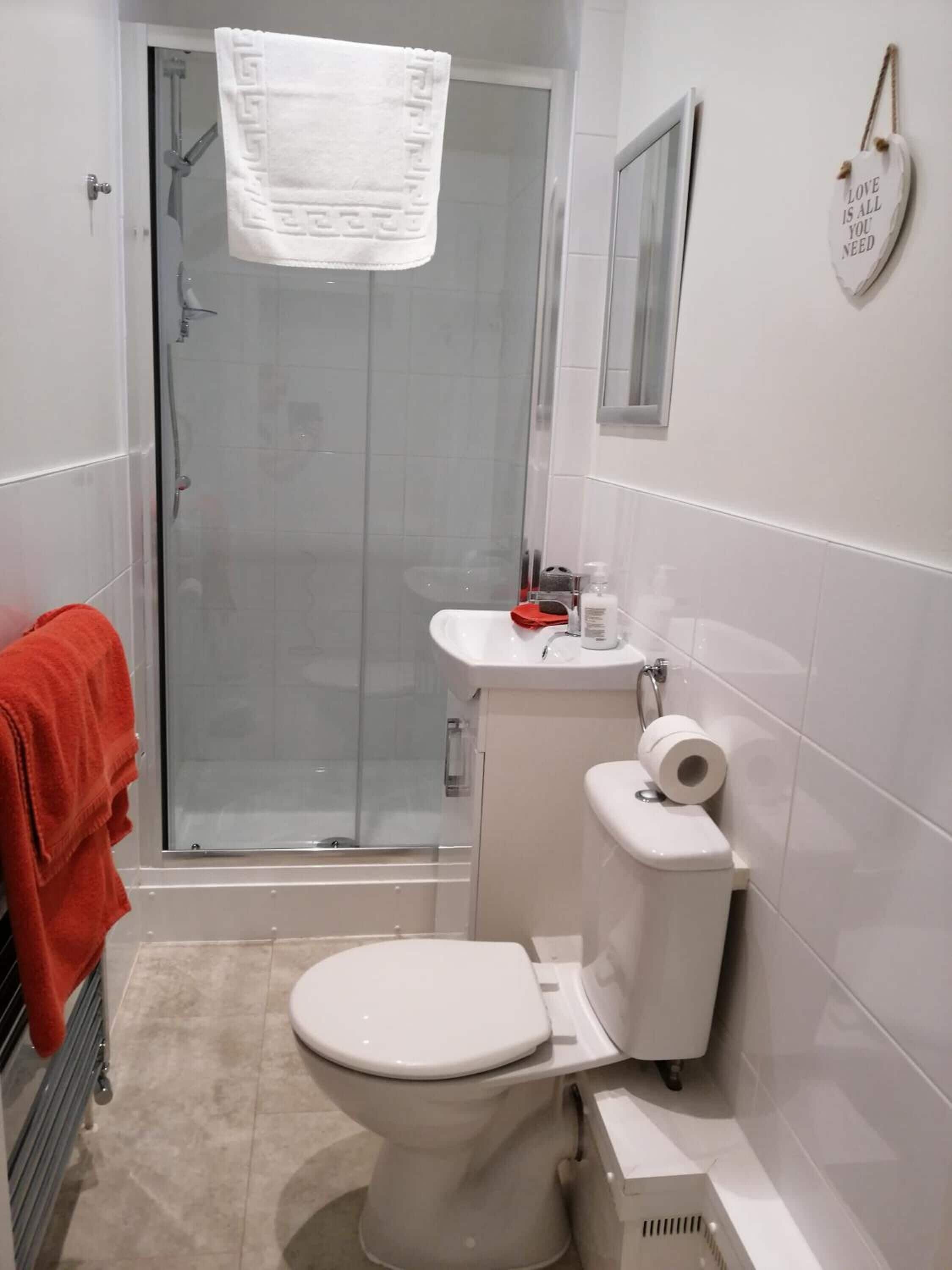 A bathroom with a glass shower enclosure, a toilet, a sink, and a towel rack.