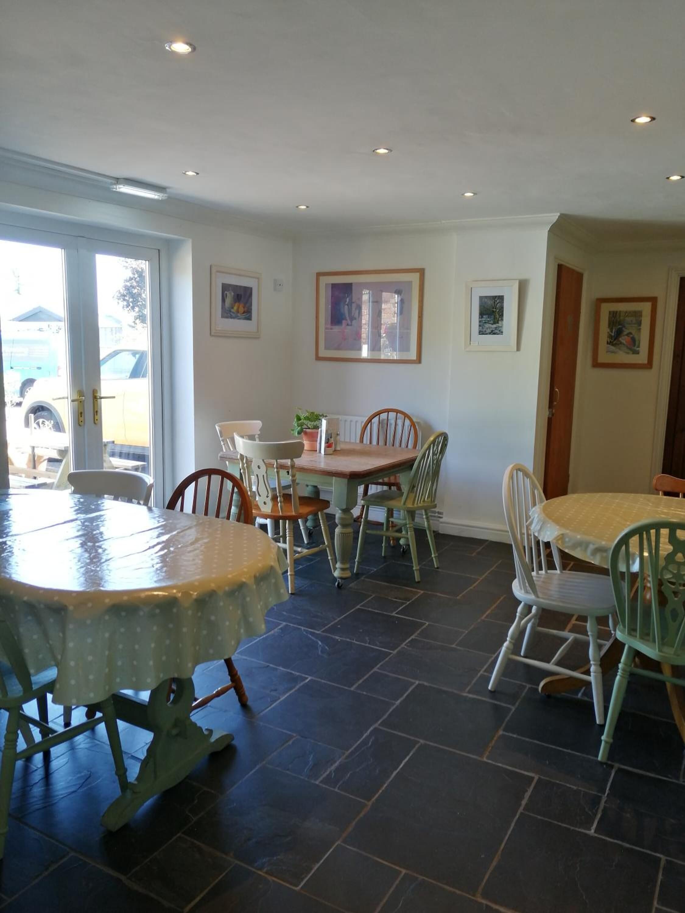 A dining area with a round table and chairs, a door leading outside, and a tiled floor.