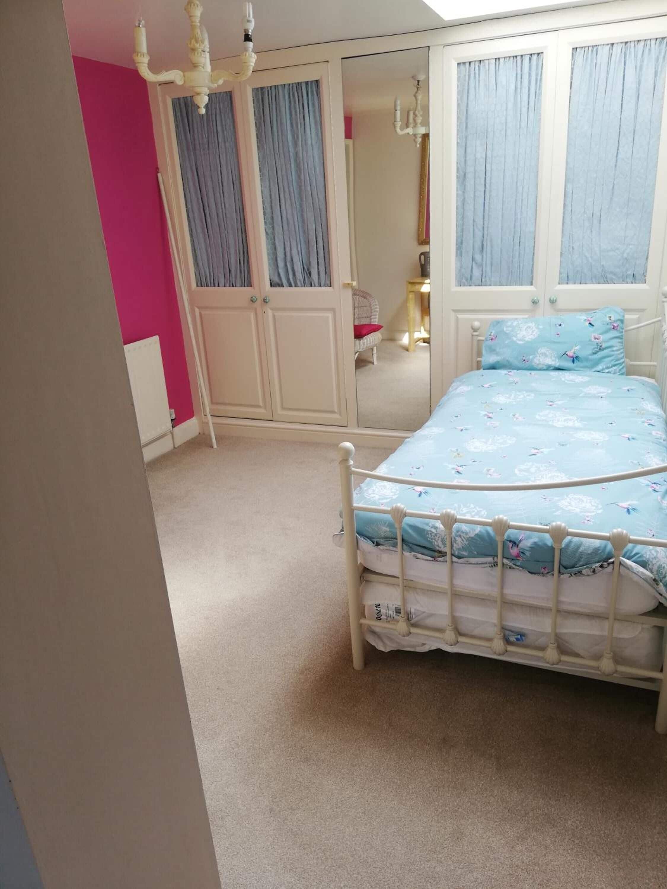 Een slaapkamer met een bed, een kledingkast en een spiegel.