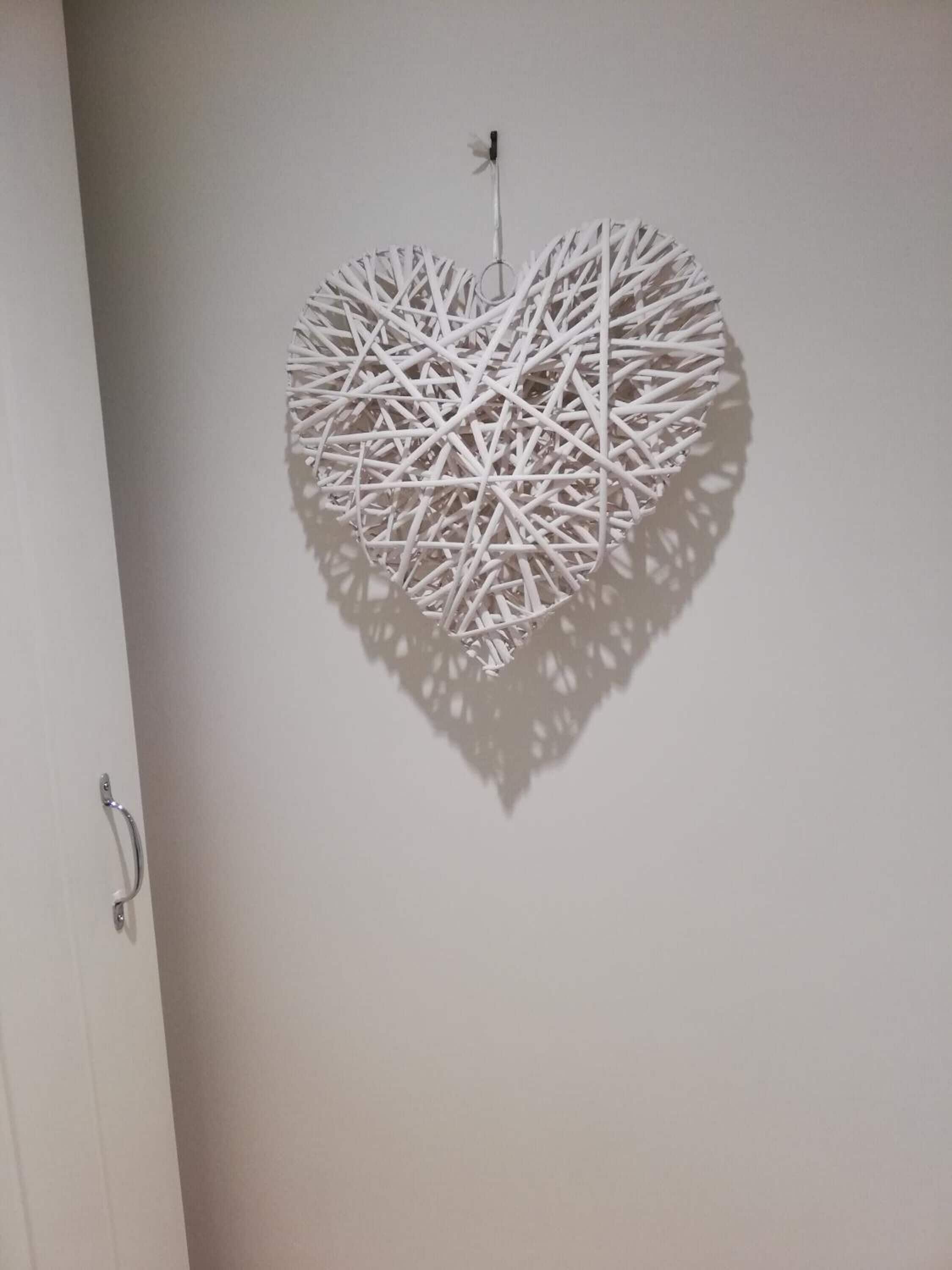A white, geometric wall hanging with a heart shape.