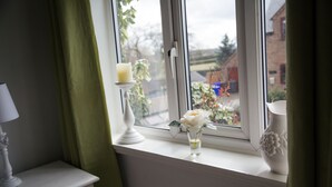 Une fenêtre avec un chandelier blanc et un vase contenant une fleur.