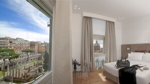 A hotel room with a large bed, a view of historic buildings, and a window with curtains. - Argentina Style View (Rome)