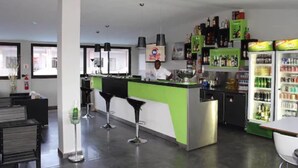 A modern bar area with a bartender, stools, and a refrigerator stocked with beverages. - Hotel Moatize (Moatize)