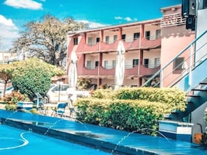 A hotel with a swimming pool, outdoor seating, and a multi-story building with balconies. - Hotel Moatize (Moatize)