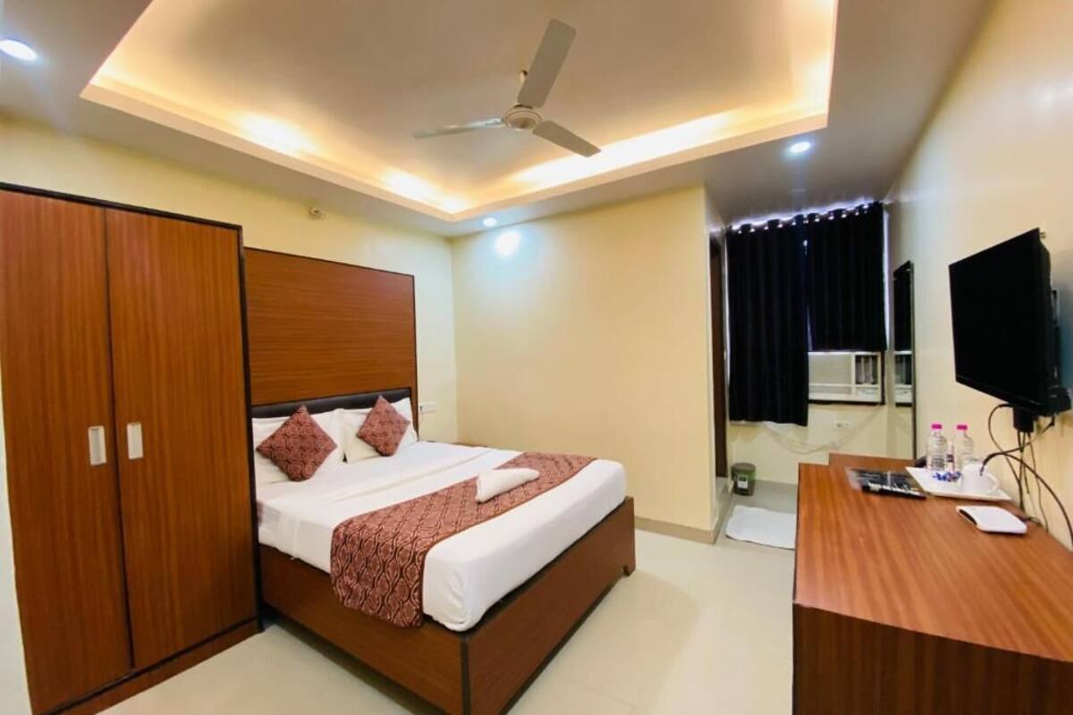 A hotel room with a bed, wardrobe, desk, and ceiling fan.