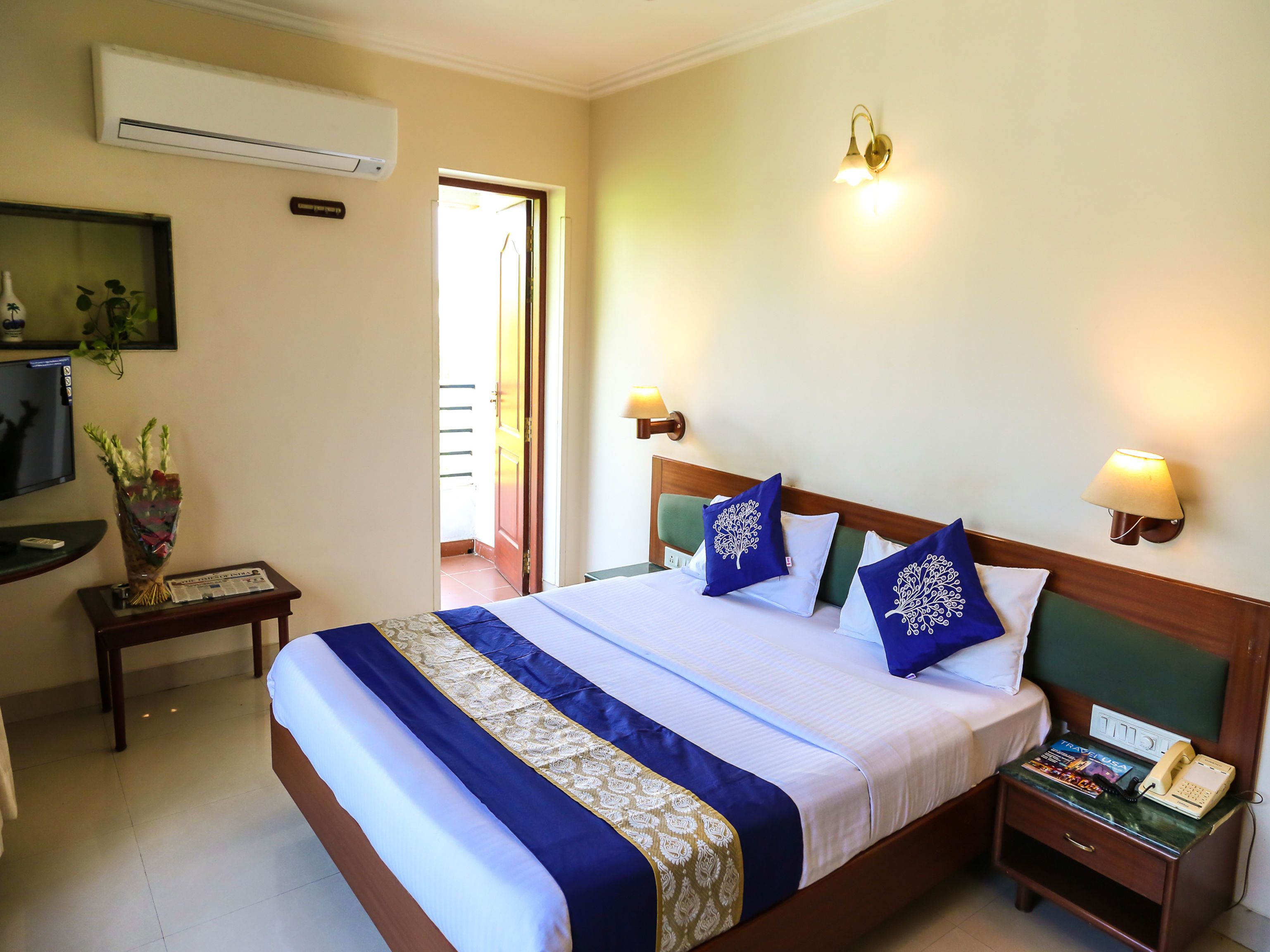 A hotel room with a bed, bedside table, lamp, and a telephone.