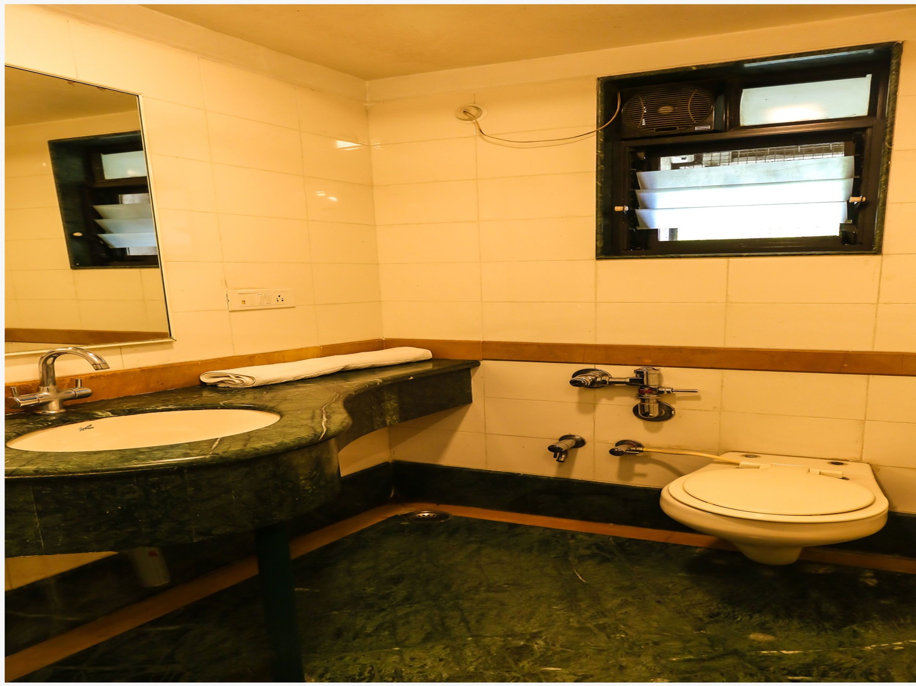 A bathroom with a sink, mirror, towel, and toilet.