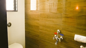 Ein Badezimmer mit Holzwand, einer Duschbrause, einer Toilette und einem Handtuchhalter.