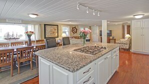 Una cocina amplia con una isla grande, armarios blancos y un comedor de madera.