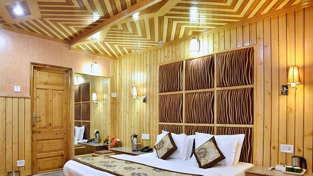 Ein holzvertiziertes Hotelzimmer mit einem großen Bett, Nachttischen, einem Spiegel und einer Wandleuchte.