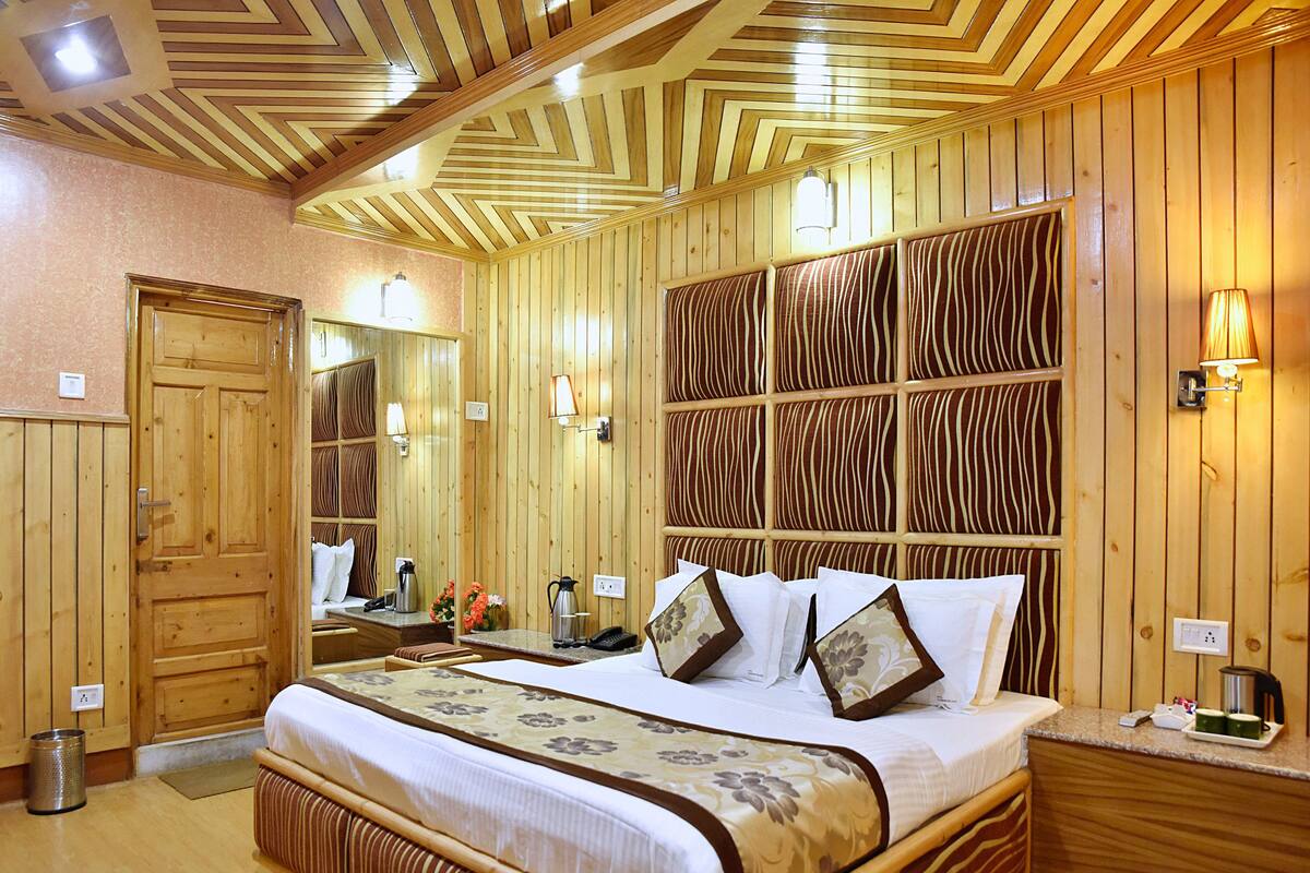 Ein holzvertiziertes Hotelzimmer mit einem großen Bett, Nachttischen, einem Spiegel und einer Wandleuchte.
