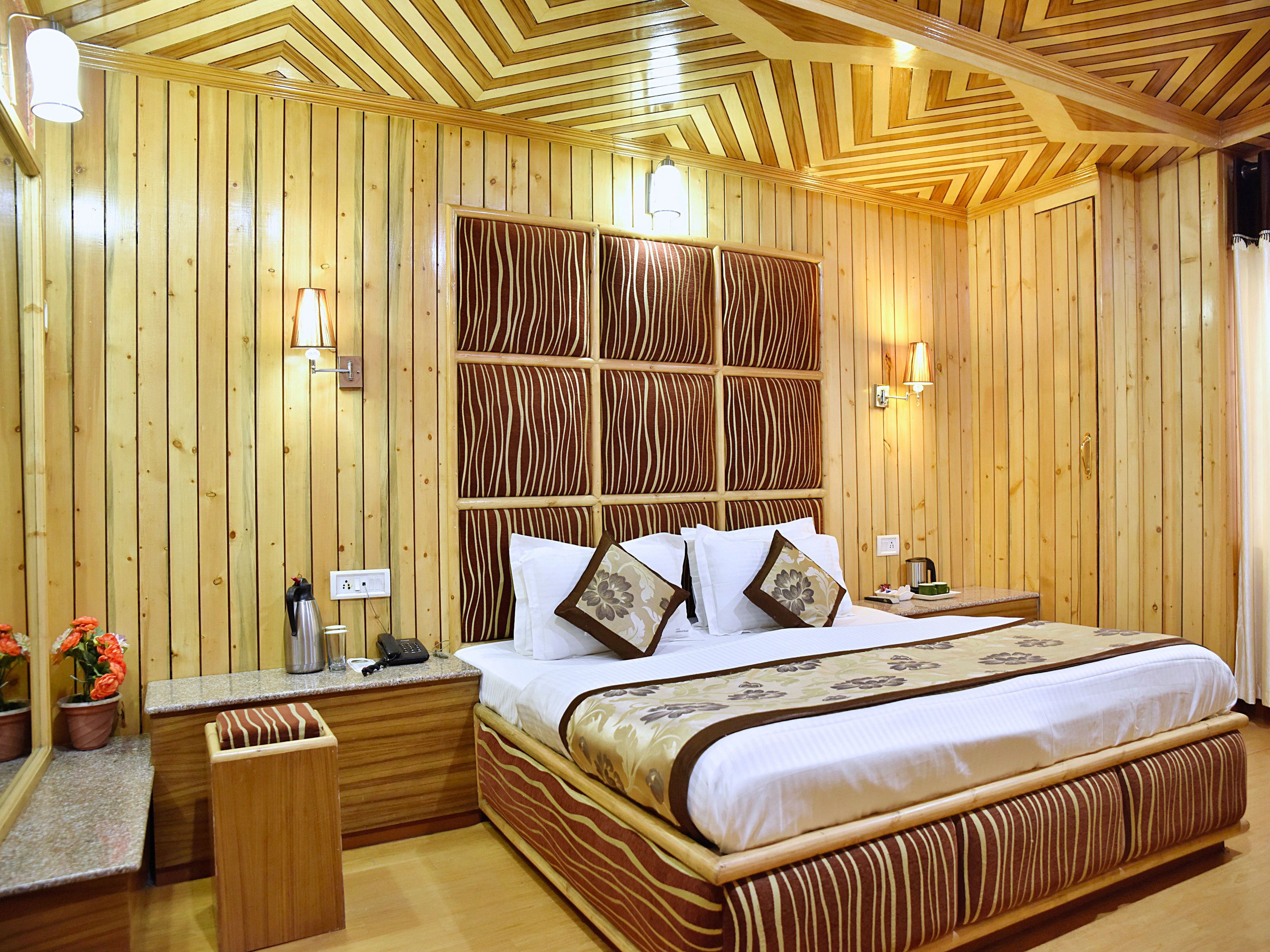 A wooden-themed bedroom with a large bed, bedside tables, and a patterned headboard.