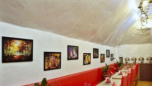 Ein Restaurant mit roten Sitzbänken, einem langen Tisch mit Stühlen und Bildern an den Wänden.