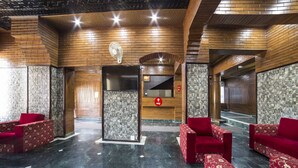 Un vestíbulo con asientos tapizados en rojo, un mostrador de recepción y una pared de piedra.