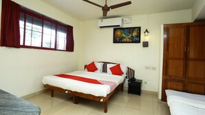 A bedroom with a bed, a ceiling fan, an air conditioning unit, a nightstand, a wardrobe, and a window with curtains. - OYO 5344 Hotel Oasis (Thiruvananthapuram)