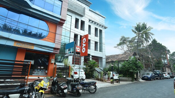 A modern building with large windows and a sign for a restaurant. - OYO 5344 Hotel Oasis (Thiruvananthapuram)