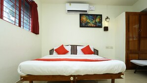 A neatly made bed with white and red bedding, a wooden headboard, and a red curtain on a window. - OYO 5344 Hotel Oasis (Thiruvananthapuram)