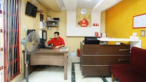 A reception area with a desk, a fan, a clock, and a sign that reads "Oasis OYO". - OYO 5344 Hotel Oasis (Thiruvananthapuram)