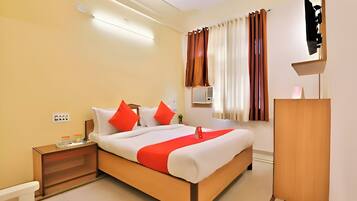 A hotel room with a large bed, a nightstand, a wooden wardrobe, and a wall-mounted TV.