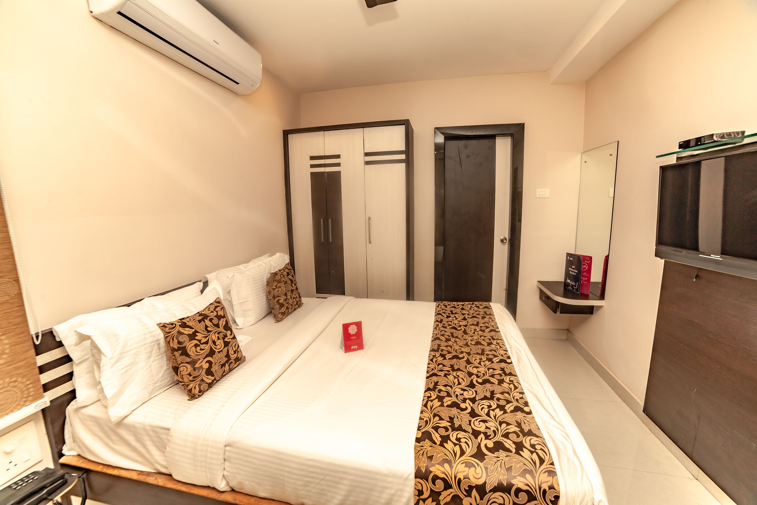 A hotel room with a bed, a bedside table, a mirror, and a wardrobe.