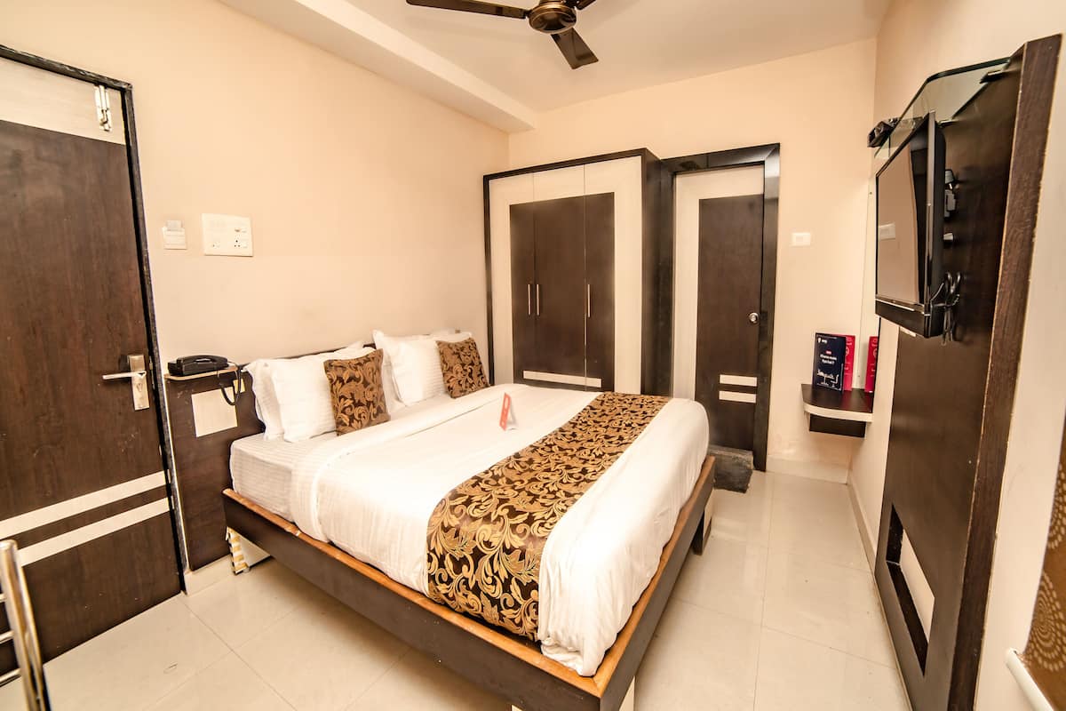 A hotel room with a bed, wardrobe, and a ceiling fan.