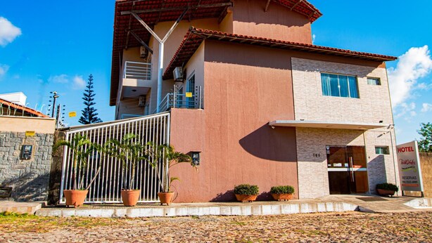 A two-story building with a red-tiled roof, a balcony, and a sign indicating it is a hotel. - Hotel Portal dos Ventos (Parnaíba)