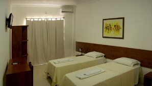 A hotel room with two single beds, a wooden desk, a mirror, and a wall-mounted air conditioner. - Hotel Portal dos Ventos (Parnaíba)