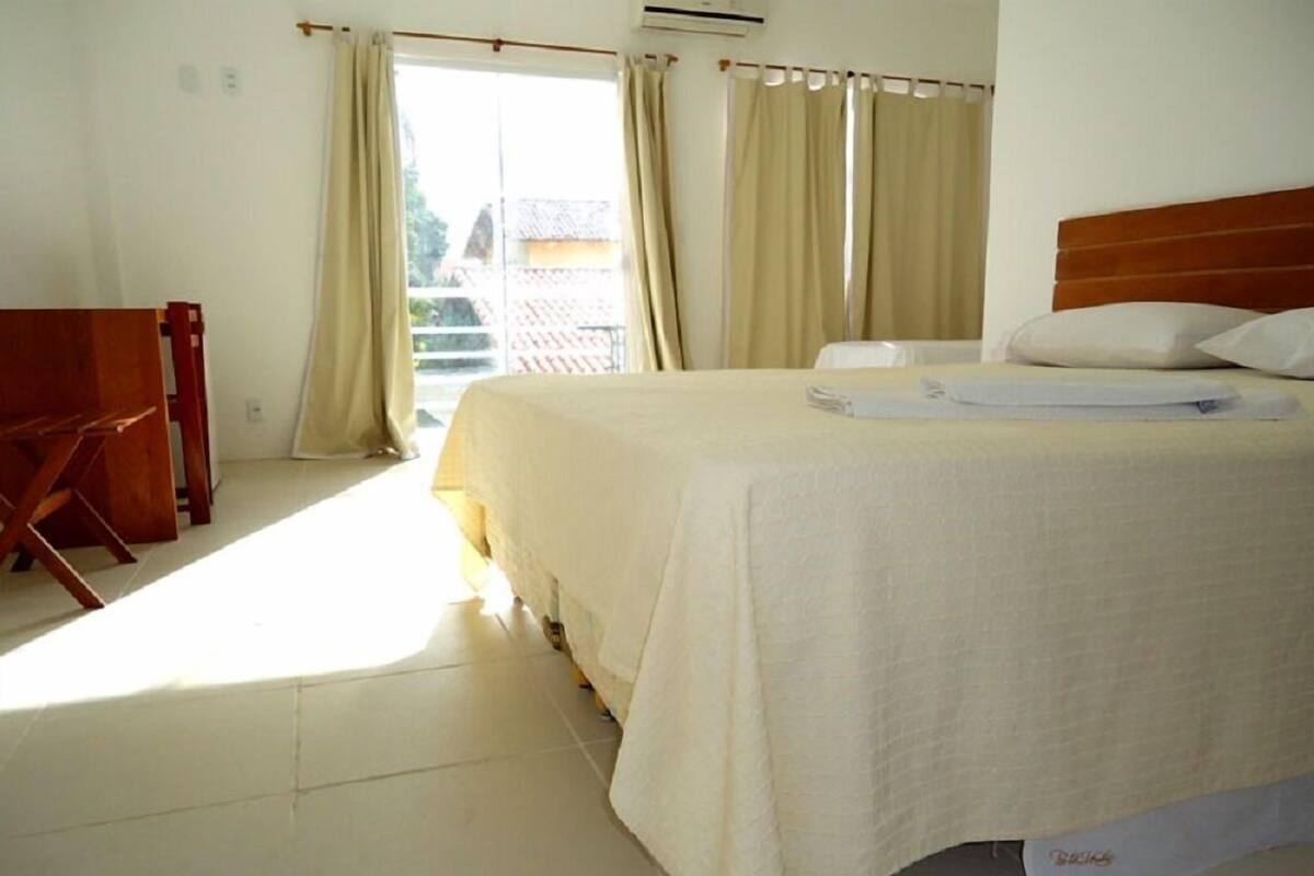 A hotel room with a large bed, a wooden headboard, and a view of a building outside through the window.