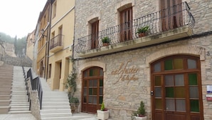 Un bâtiment à la façade en pierre, aux volets en bois et à l’enseigne indiquant « calfuster de la plaga ».