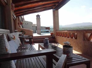 Un balcon doté de mobilier en bois, offrant une vue sur le paysage et présentant un style architectural rustique.