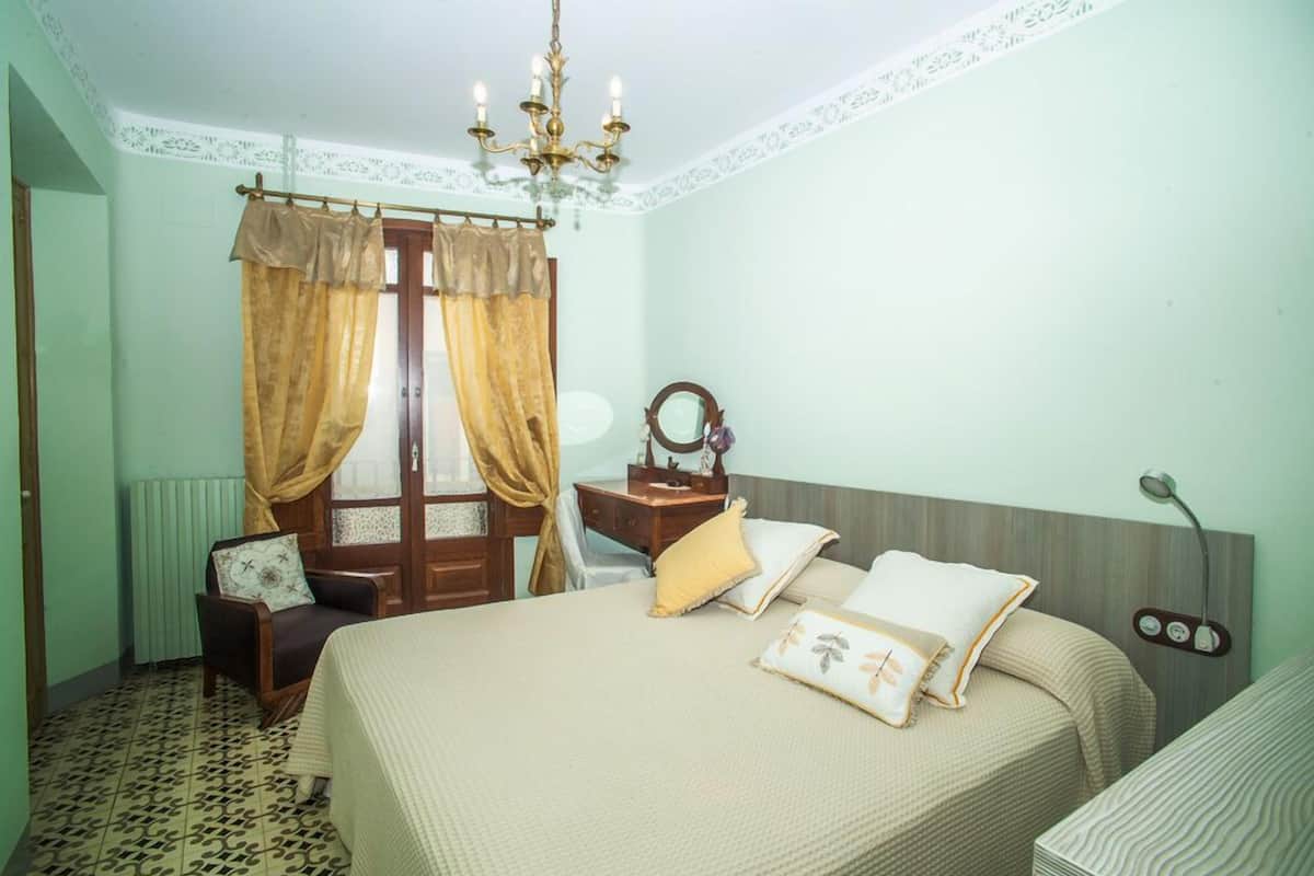 Une chambre à coucher comprenant un lit, une table de chevet, une chaise, un miroir et un lustre.