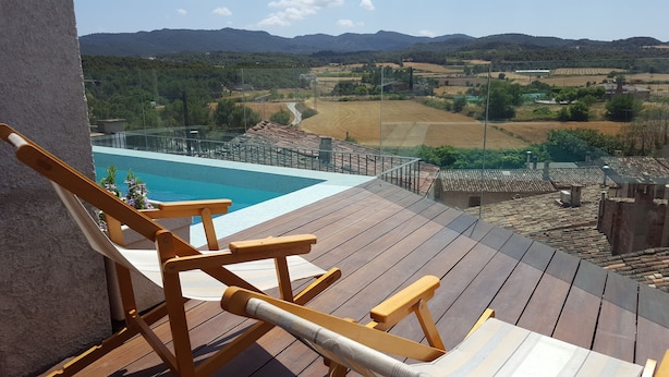 Une terrasse en bois avec une piscine, offrant une vue sur un paysage rural composé de champs et de montagnes.