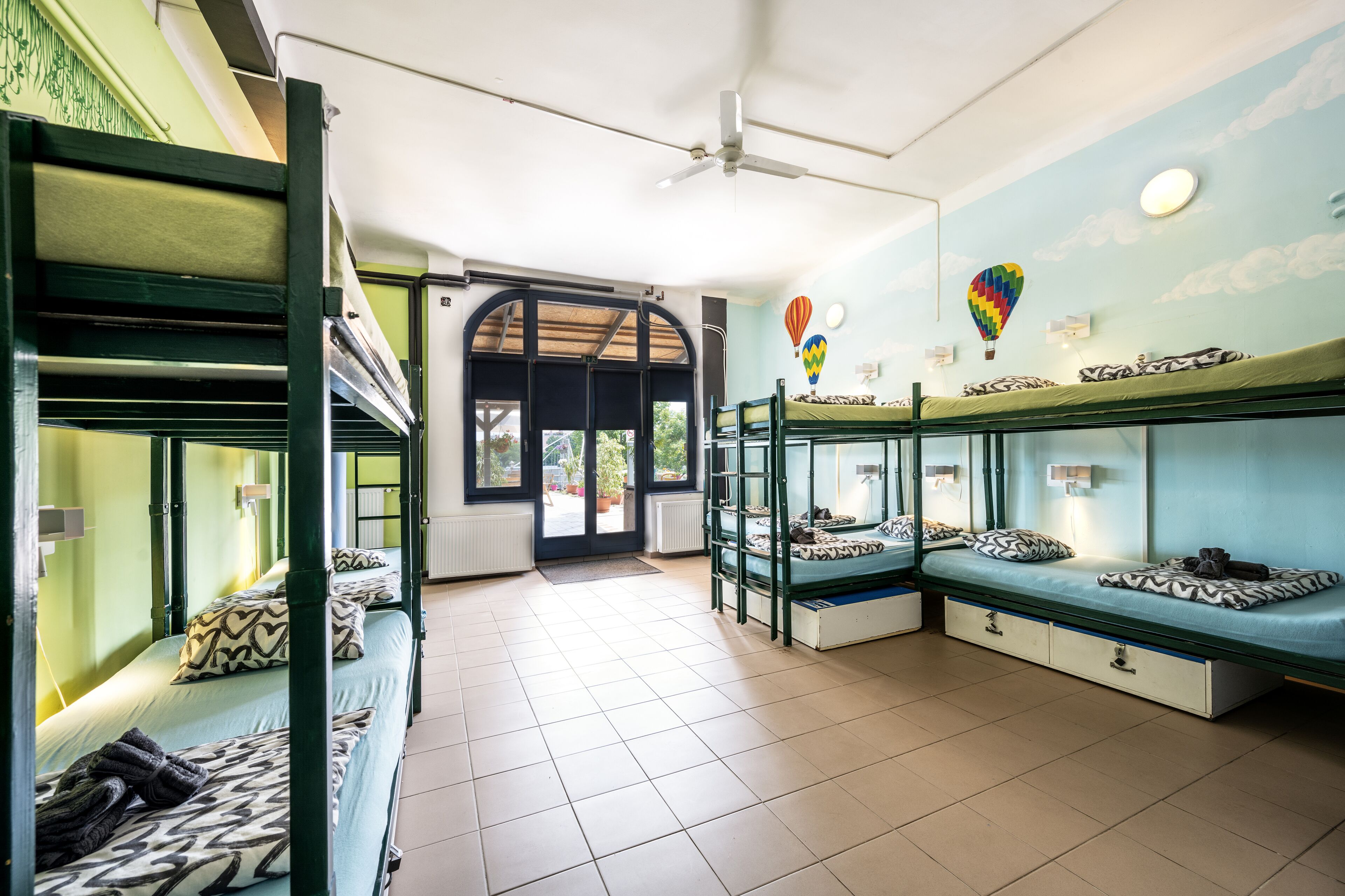 Un dormitorio con literas, ventilador de techo y vistas al exterior.