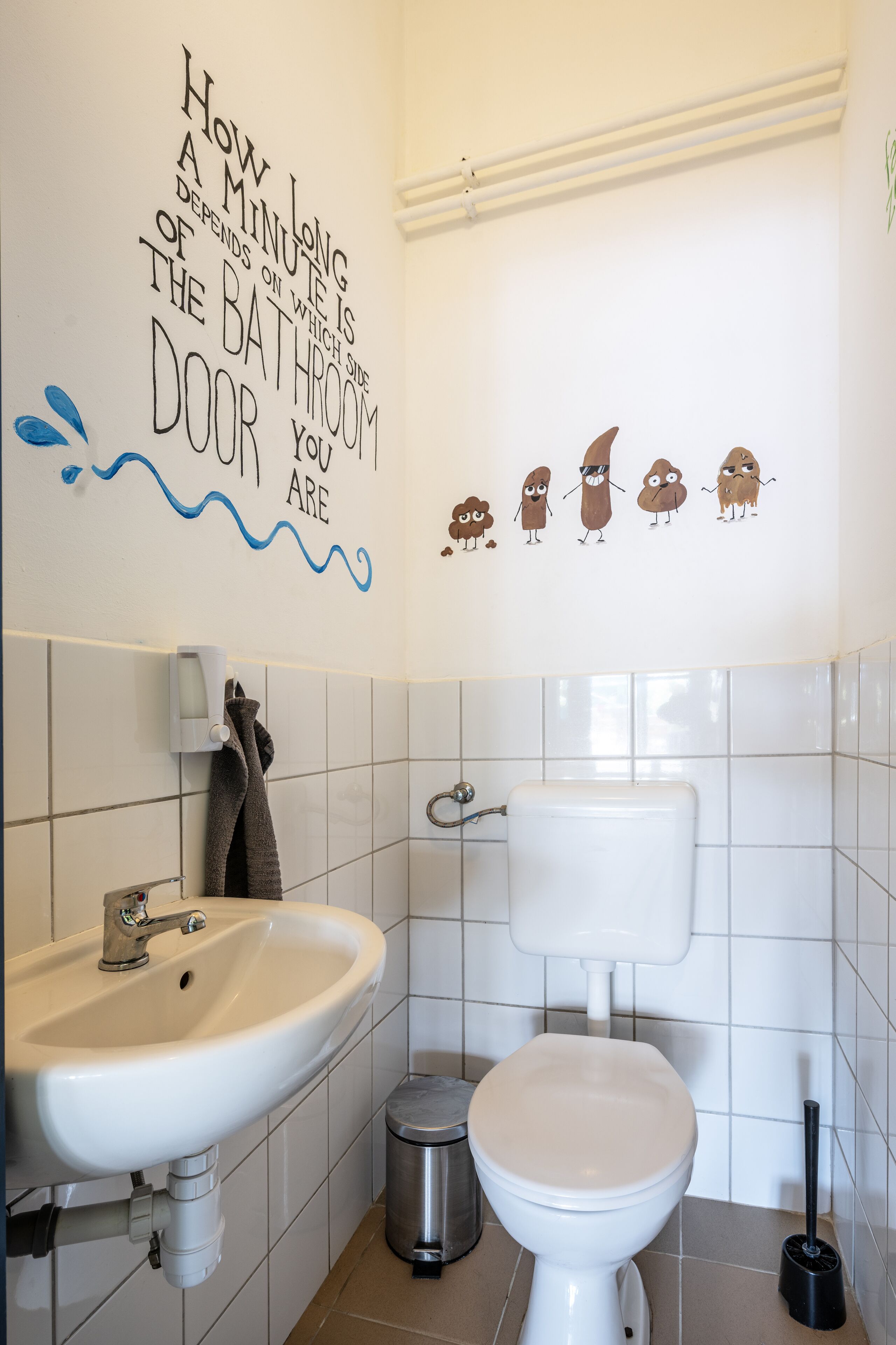 Een badkamer met een wastafel, toilet en een muurstickers met tekenfilmfiguren.