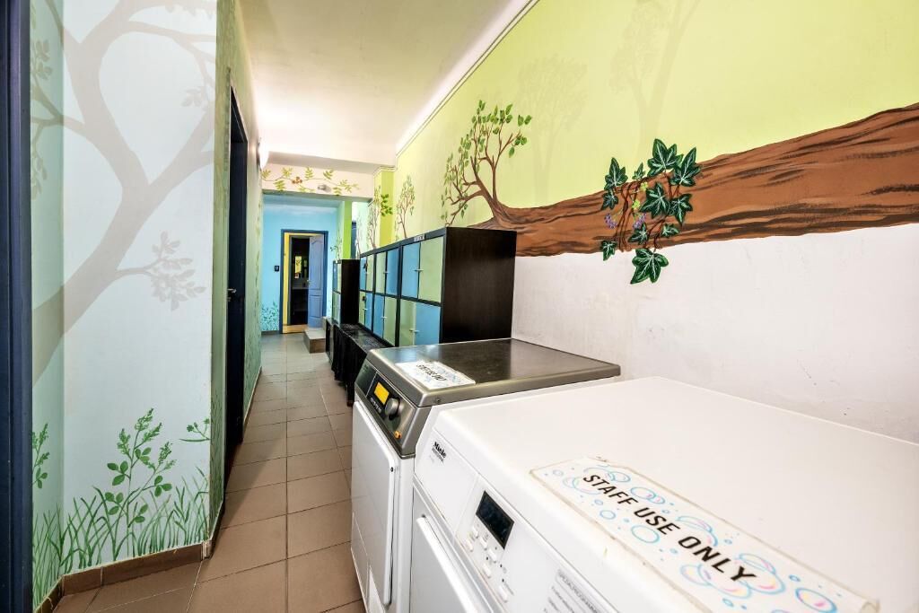 Un área de lavandería con lavadora y secadora, un armario y una pared con un mural de un árbol.