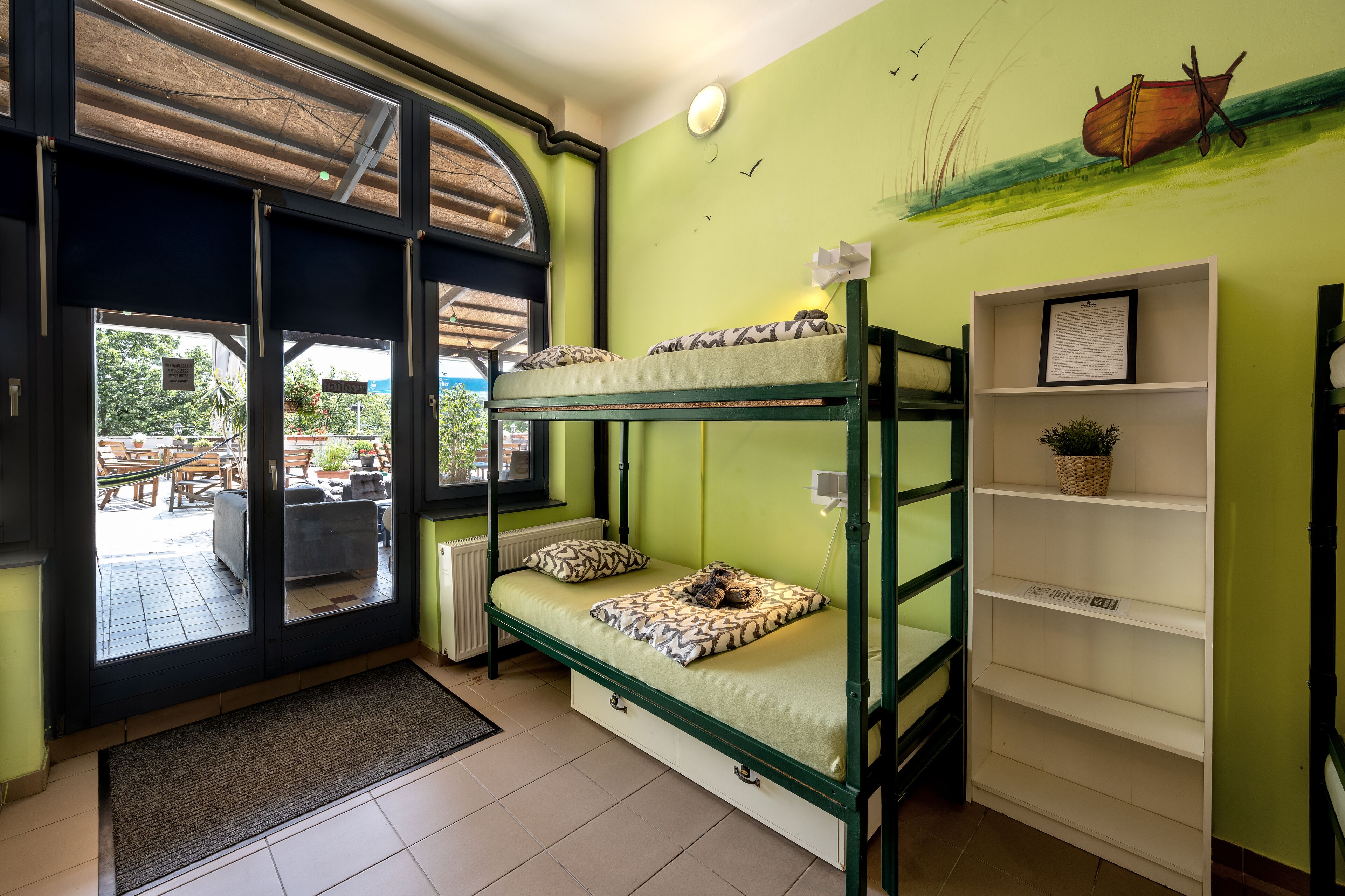Habitación con literas y vista al exterior, una repisa con una cesta y un cuadro en la pared.