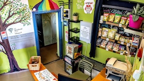 A hostel interior with a tree mural, a wall clock, a snack shelf, and a desk with a computer. - Island Hostel - Adults only (Budapest)