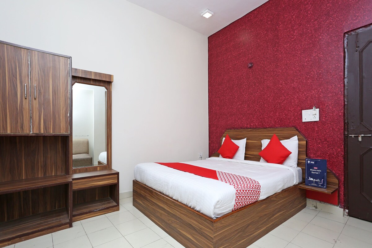 A bedroom with a wooden bed, red and white bedding, a red textured wall, and a wardrobe.