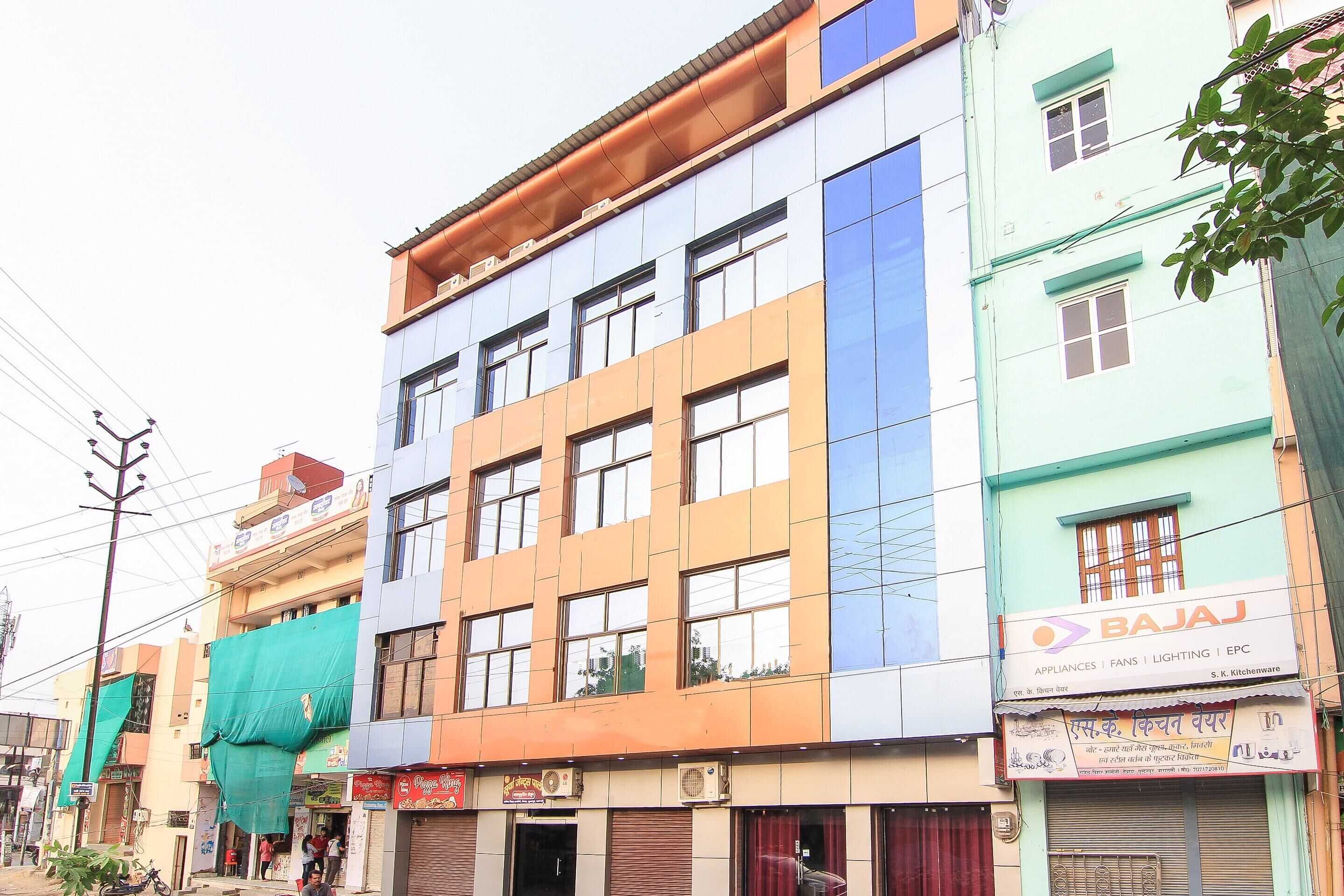 A multi-story building with various shops on the ground floor, including a Bajaj sign.