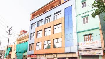 A multi-story building with various shops on the ground floor, including a Bajaj sign.