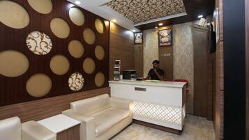 A reception area with a sofa, a reception desk, and a patterned wall.