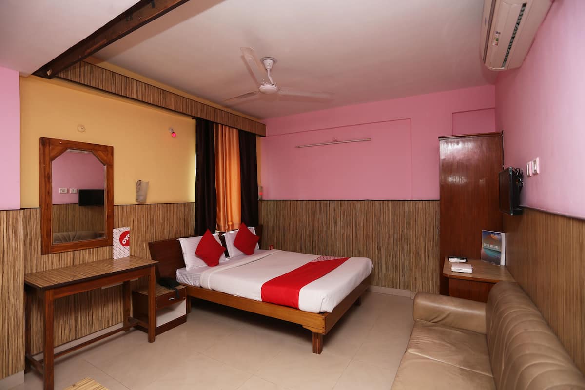 Ein Hotelzimmer mit einem Bett, einem Holztisch, einem Spiegel, einem Fernseher und einem Sofa.