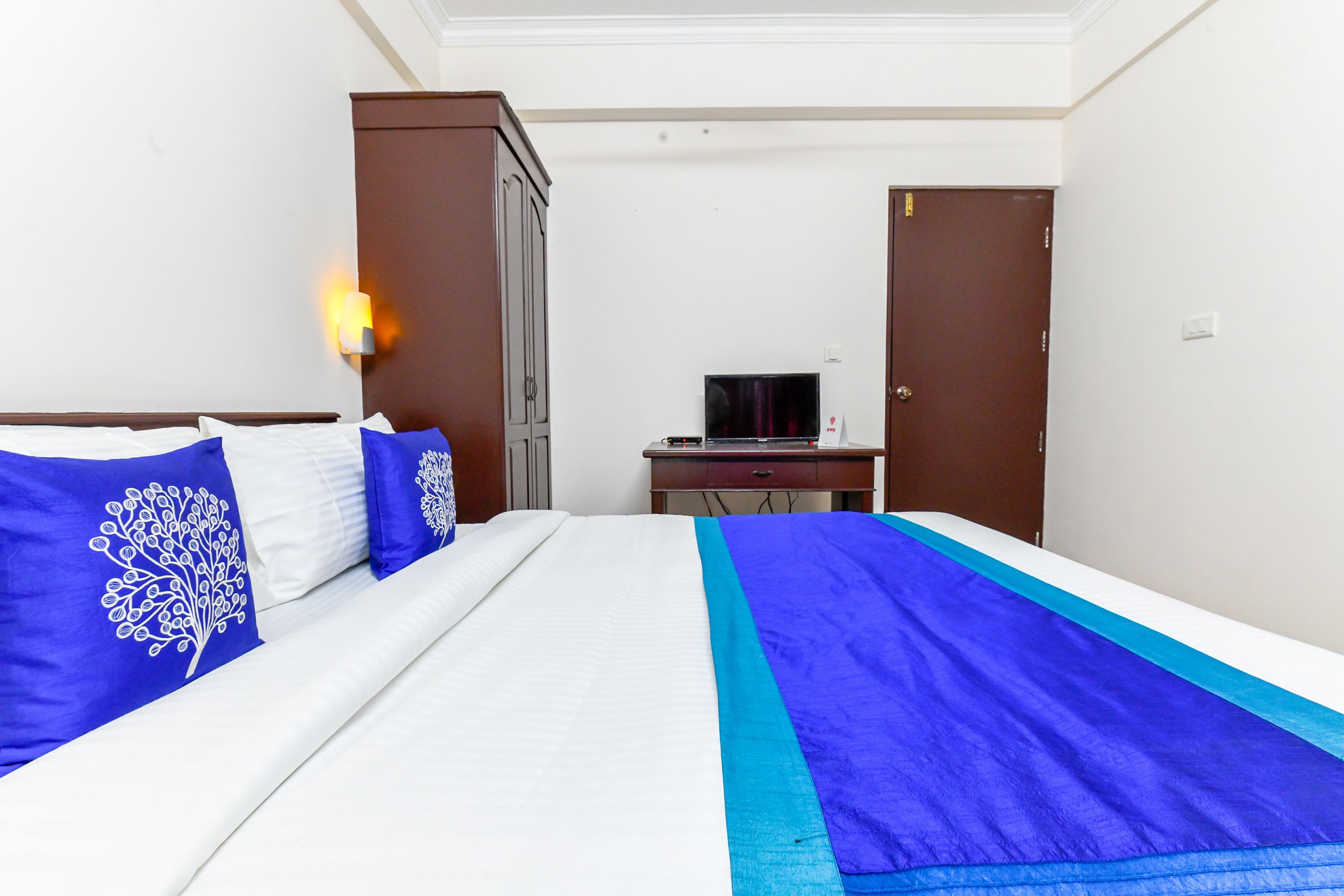 A hotel room with a bed, a TV, a wardrobe, and a desk.