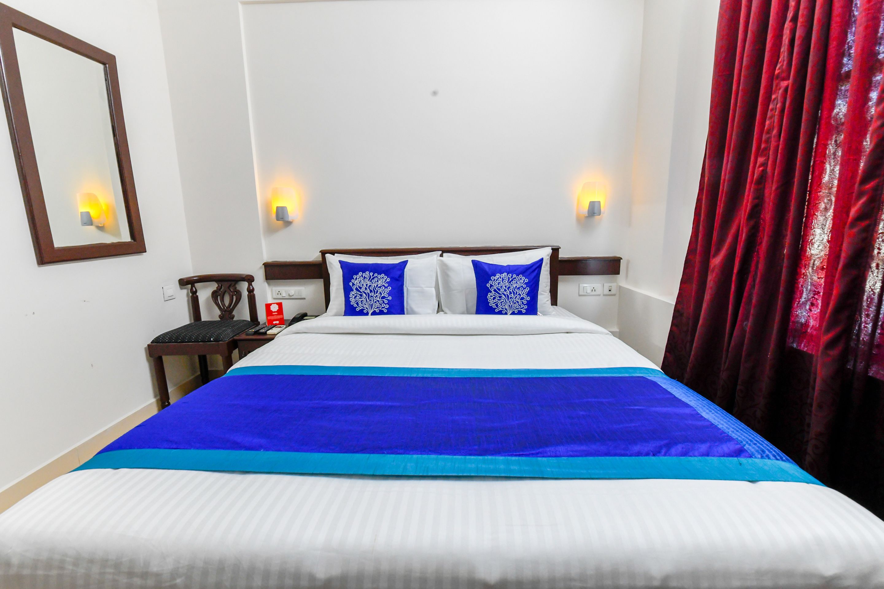 A neatly made bed with a blue and white bedspread, two blue pillows, and a wooden headboard.